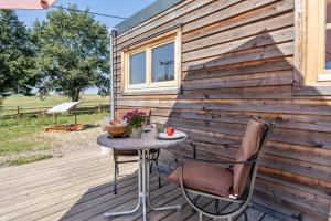 a table and chairs on a deck with a wall at Tinyhaus im Eselgarten in Lommatzsch