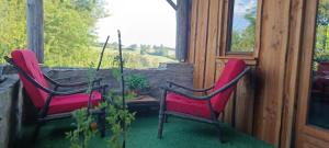 two red chairs sitting on a porch with a window at La chouette in La Malonie