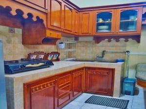 Villa Luxury kota bunga في Cikundul: مطبخ مع خزائن خشبية ومغسلة