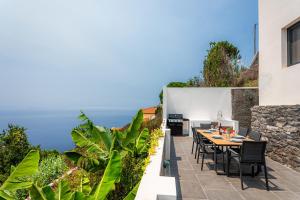 a patio with a table and chairs and the ocean at Meerblick - 3-Bett Villa mit Terrassen & Hot-Tub in Fajã da Ovelha