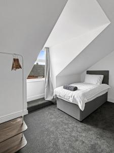 une chambre blanche avec un lit et une fenêtre dans l'établissement Amaya One -3 bedroom townhouse - with garden - close to town centre - sleeps 7, à Grantham