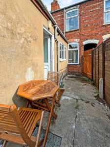 une table et des chaises en bois à côté d'un bâtiment dans l'établissement Amaya One -3 bedroom townhouse - with garden - close to town centre - sleeps 7, à Grantham