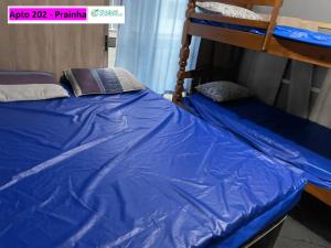 a bedroom with two bunk beds with blue sheets at Arraial do Cabo - Prainha - Aluguel econômico in Arraial do Cabo