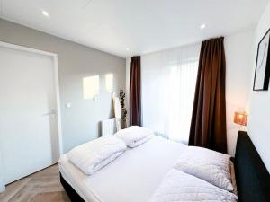 białe łóżko w sypialni z oknem w obiekcie Ukiyo I Ontspannen in Modern Huis met Tuin op de Veluwe w mieście Ermelo