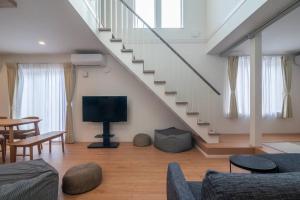 een woonkamer met een tv en een trap bij 新屋 札幌中心薄野車程4分鐘 挑高設計客廳 和室空間 可停車2台 高速WiFi 豐平川河岸旁 in Toyohira