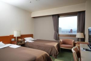a hotel room with two beds and a window at Matsuzaka Frex Hotel in Matsuzaka
