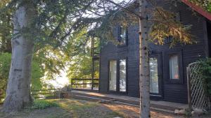 a black house with a porch and a tree at Zakontek Lubkowa in Lubkowo