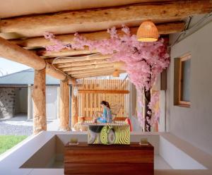 济州市Tebah Stay的房间里，一位女士坐在木质天花板下的长凳上