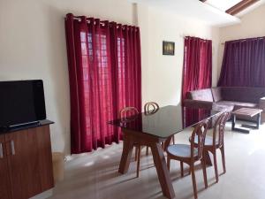 a living room with a table and a couch and red curtains at Whiteflower Mountain Resort in Perintalmanna