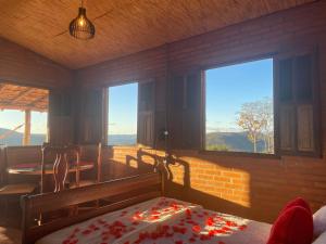 una camera da letto con un letto in una stanza con finestre di Chalé Mirante da Serra a Sabará Altre 23 foto