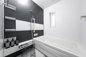 ein weißes Badezimmer mit Badewanne und Fenster in der Unterkunft The Exeparel in Kushiro