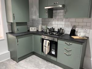 a kitchen with green cabinets and a stove at Spacious Home - Sleeps 5 persons - Minutes Walk from Anfield Stadium in Liverpool +28 photos