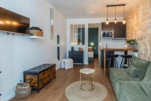 a living room with a green couch and a kitchen at Île SAINT LOUIS, NOTRE DAME, suite 1 chambre 2 à 4p in Paris +6 photos