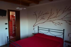 RoddinoにあるAgriturismo Ra Nissoraの赤いベッドが備わるベッドルーム1室(壁に枝付)