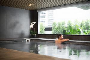 a woman in a swimming pool in a building at Avani Ratchada Bangkok Hotel in Bangkok +31 photos