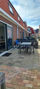 een patio met een tafel en banken en een gebouw bij 103B nieuwe vakantie woning met sauna vanaf juli 2024 in Westkapelle