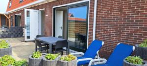 a patio with blue chairs and a table and some plants at 103C nieuwe vakantiewoning met sauna in Westkapelle