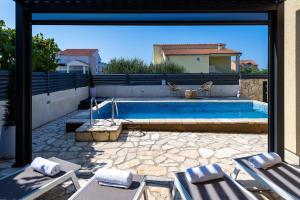 een patio met een zwembad en 2 ligstoelen bij Apartment Dora family only in Vodice