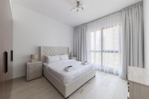 ein weißes Schlafzimmer mit einem großen Bett und einem Fenster in der Unterkunft 1bd Partial Burj Al Arab View Prime Location in Dubai + 26 Fotos