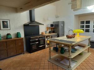 a kitchen with a stove and a table in it at Longere ancienne dans un parc in Plogonnec