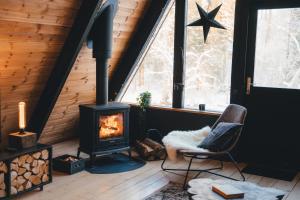 a room with a stove and a chair in front of a window at Two Black Cabins in Pabaži +65 photos