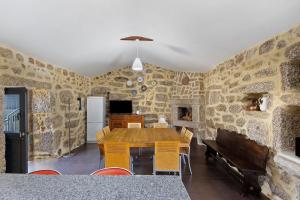 ein Esszimmer mit einem Tisch und einer Steinwand in der Unterkunft Quinta de Ramil in Rossas