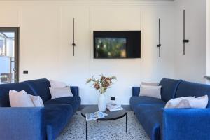 a living room with two blue couches and a tv at Elvezia Boutique in Baveno