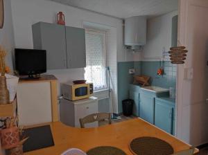 a small kitchen with a table and a microwave at Le nid douillet Champêtre Linge fourni in La Bourboule