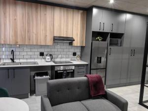 a kitchen with a couch and a sink and a refrigerator at Ultra-Modern Studio Apartment in Table View