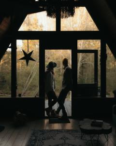a couple walking in front of a window at Two Black Cabins in Pabaži