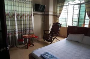 a bedroom with a bed and a chair and a table at Thanh Lich Guesthouse in Quảng Ngãi