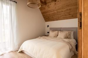 a bedroom with a white bed with a wooden ceiling at NOOK Cabins - Mountain View in Zakopane