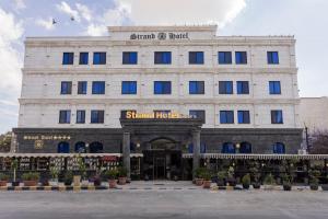 a large white building with a sign on it at Strand Hotel Jordan in Amman