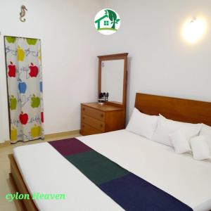a bedroom with two beds and a dresser and a mirror at Ceylon Heaven in Wadduwa