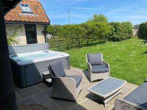 a patio with a hot tub and two chairs at Samphire Cottage in Stiffkey
