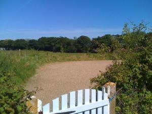 a white fence next to a dirt road at Samphire Cottage in Stiffkey