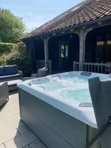 a large hot tub in front of a house at Samphire Cottage in Stiffkey