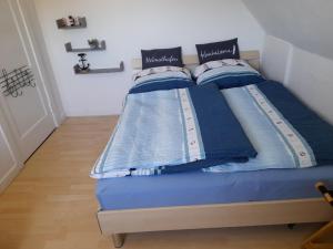 a bed with blue sheets and pillows on it at Pension Entenhausen in Schwentinental