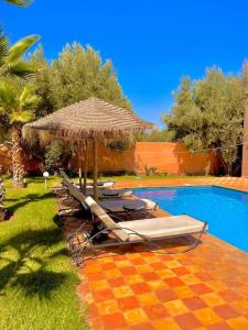 a group of lounge chairs and an umbrella next to a pool at Villa des tortues 3 Marrakech piscine chaufée privative sans vis à vis in Marrakesh