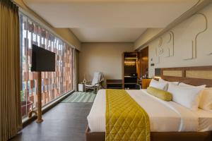 a hotel room with a bed and a large window at Fressotel, Kanakapura Road in Bengaluru