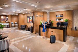 a woman standing at a reception desk in a hotel lobby at Landmark Creek Hotel & Wellness Plovdiv in Plovdiv