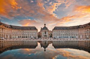a large building with a reflection in the water at Bel appartement Bordeaux centre in Bordeaux