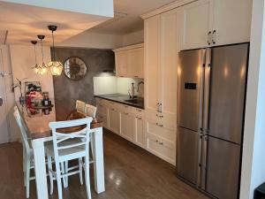 a kitchen with a table and a stainless steel refrigerator at Seaside Court Retreat By IsrApart in Tel Aviv