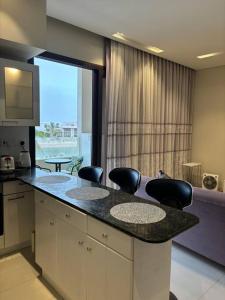 a kitchen with a counter with chairs and a large window at Hawana Salalah Resort - Acacia 51 in Ma‘mūrah +5 photos