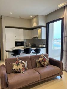 a living room with a brown couch and a kitchen at Hawana Salalah Resort - Acacia 51 in Ma‘mūrah