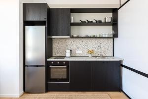 a kitchen with black cabinets and a refrigerator at Soho Residence by halu! in Thessaloniki
