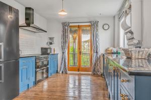 a blue kitchen with blue cabinets and a door at Samphire Cottage in Stiffkey +34 photos