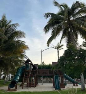 einen Spielplatz mit Rutsche in einem Park mit Palmen in der Unterkunft Hawana Salalah Resort - Riviera 3 in Salalah