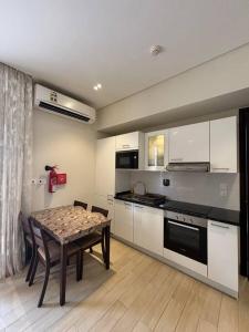 eine Küche mit Tisch und eine Küche mit weißen Schränken in der Unterkunft Hawana Salalah Resort - Riviera 3 in Salalah