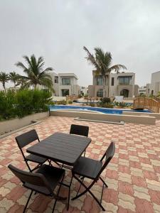 einen schwarzen Tisch und Stühle auf einer Backsteinterrasse in der Unterkunft Hawana Salalah Resort - Riviera 3 in Salalah